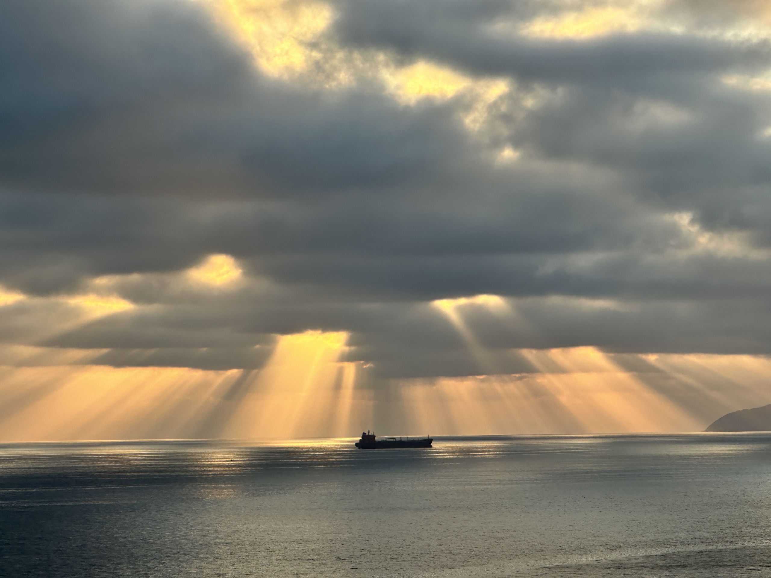 Sunlight breaking through dark storm clouds over the ocean—a visual metaphor for finding light and resilience even when difficult conditions surround us